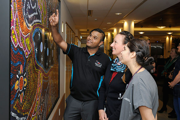 Artist Justin Martin shows Joondalup Health Campus staff the ‘collective canvas’ at the launch of NAIDOC Week activities at the hospital.